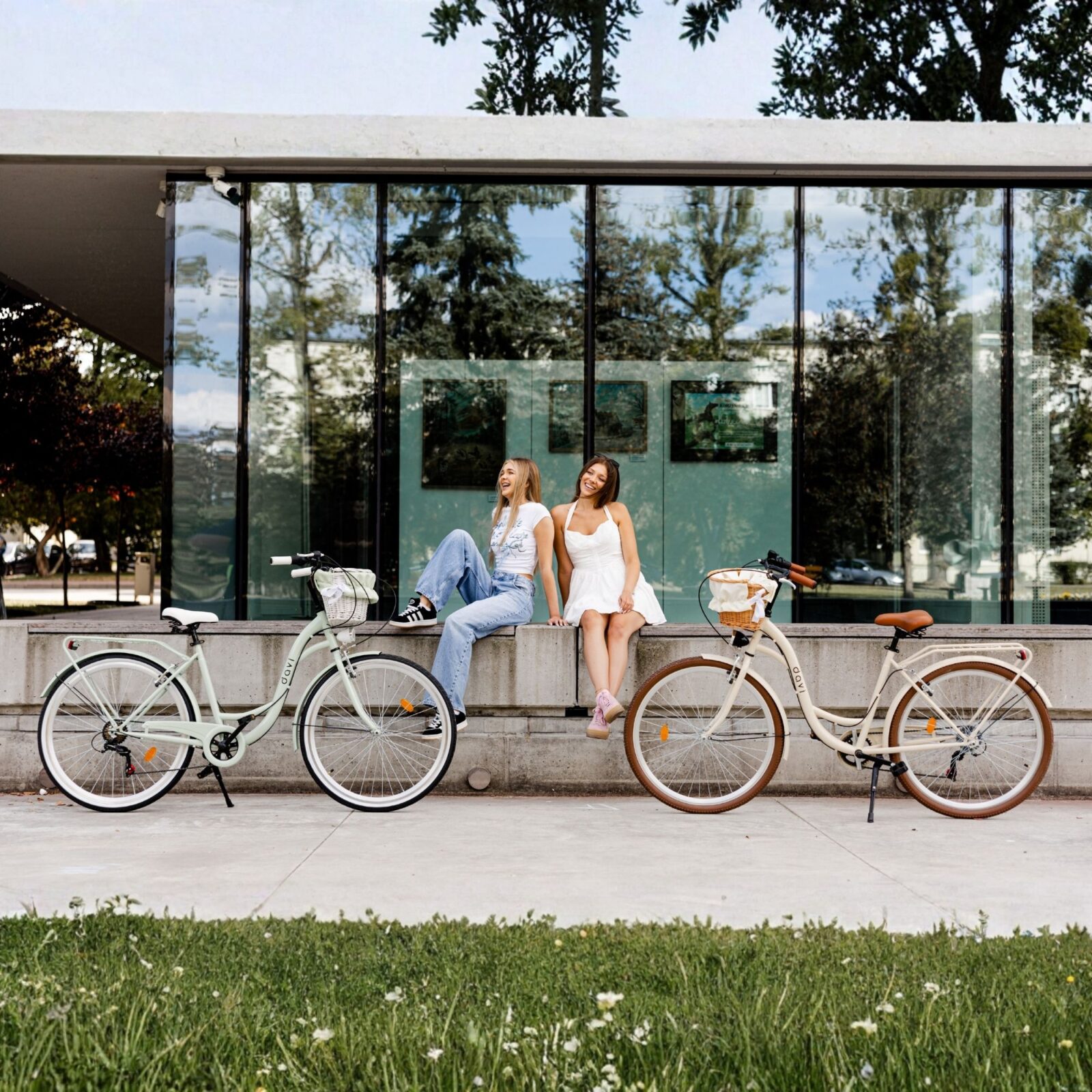 Nők biciklik mellett modern épület előtt.