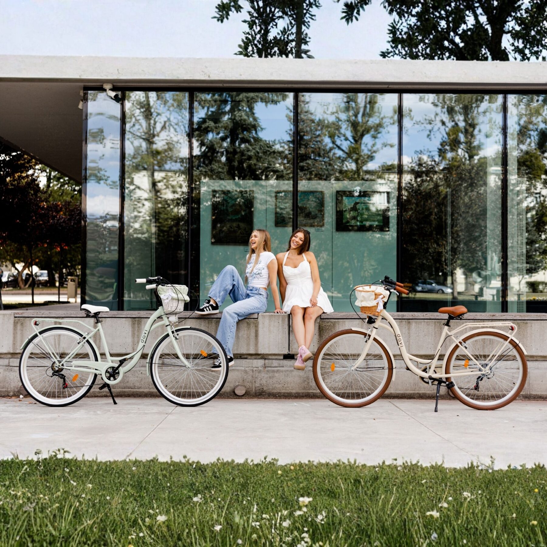 Nők biciklik mellett modern épület előtt.